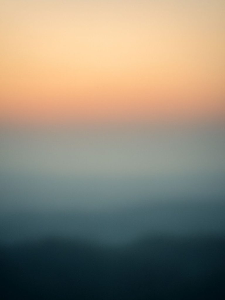 A softly blurred horizon at dawn with warm and cool tones blending together, symbolizing the unknown, spiritual transformation, and healing through forgetting.
